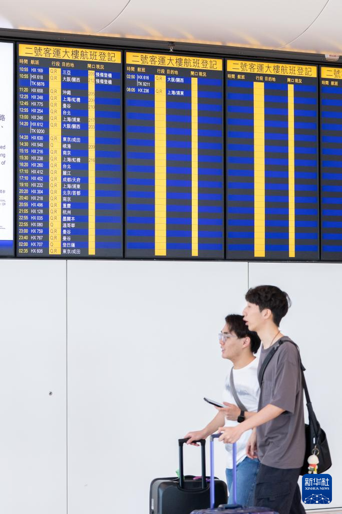 5月27日，旅客从香港国际机场二号客运大楼离境大堂航班信息显示屏前走过。
