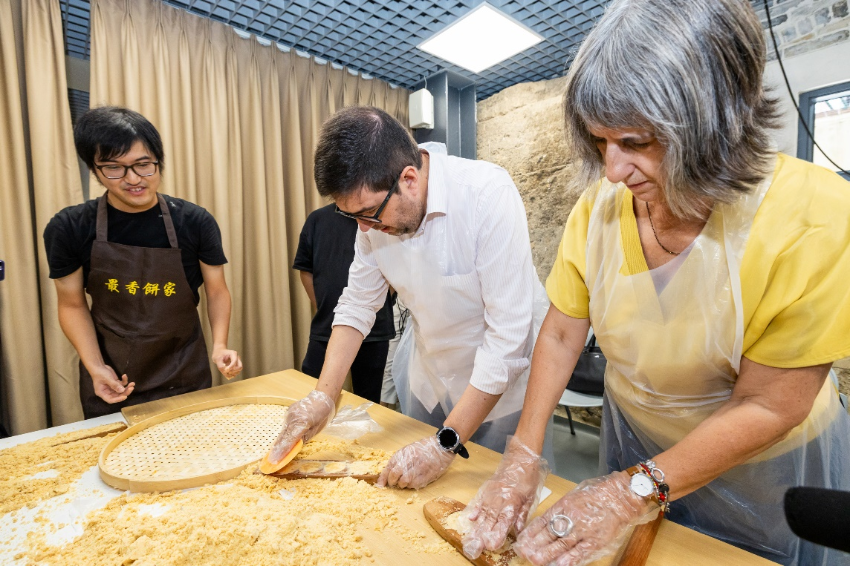 图为代表团体验非物质文化遗产项目杏仁饼制作技艺。