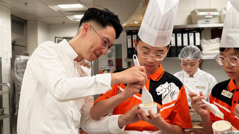 图为吴梓佑同学(左二)在父亲吴永谋(左一)指导下制作甜品。 图为吴梓佑同学(左二)在父亲吴永谋(左一)指导下制作甜品。