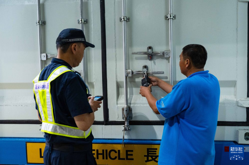 8月26日，澳门海关工作人员（左）与货车司机解锁安全智能锁。