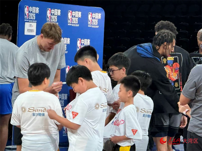 图为NBA球员爽快地为孩子们在球衣上签名留念。 图为NBA球员爽快地为孩子们在球衣上签名留念。