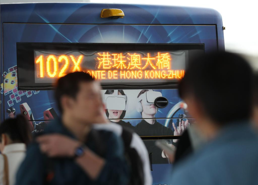 市民和旅客在横琴口岸澳门口岸区排队，准备登上前往港珠澳大桥方向的公交车。