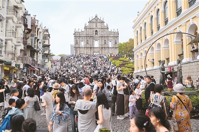 旅客在澳门大三巴牌坊前游览。