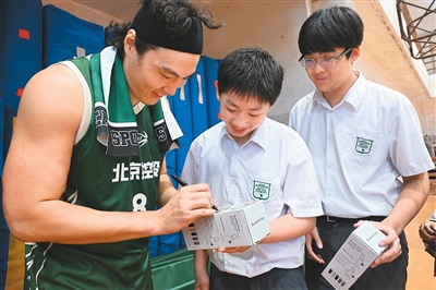 图为北控男篮球员（左一）为培侨中学学生签名。