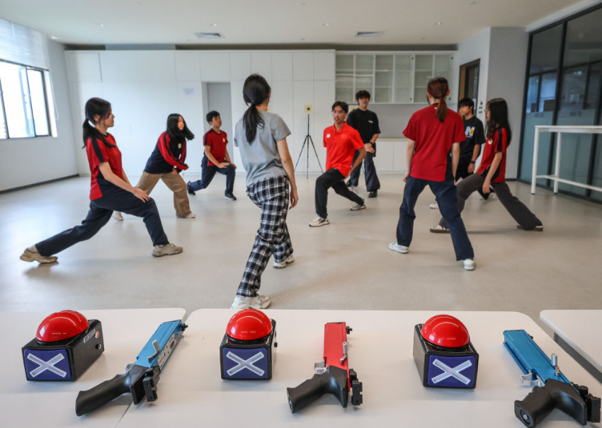 ↑图为广东现代五项运动协会教练员滕泽华（中）带领广州市中黄港澳子弟学校学生进行拉伸训练（6月19日摄）。
