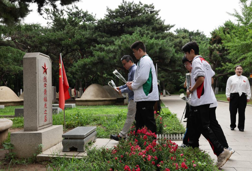 7月2日，在沈阳的抗美援朝烈士陵园，香港培侨中学校长伍焕杰和学生一起向烈士墓献花。