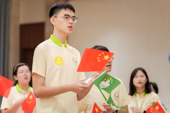 图为同学们在联欢会上挥舞国旗区旗唱响《我和我的祖国》。