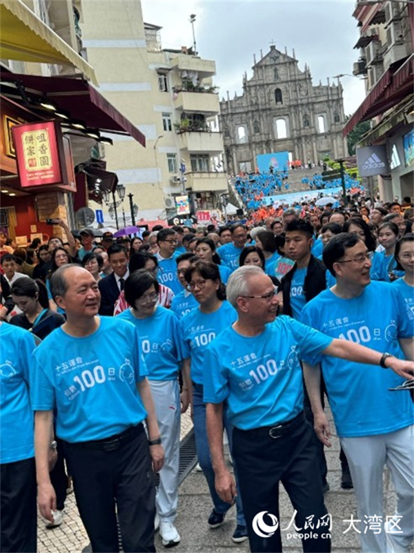 图为岑浩辉身穿蓝色运动背心，精神抖擞与众人一同从大三巴牌坊起步，参与“迎百日 健步行”活动。