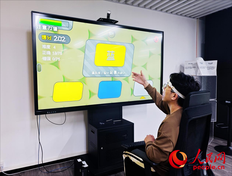 广州琶洲实验室工作人员演示脑机接口设备如何操作专注力训练游戏。