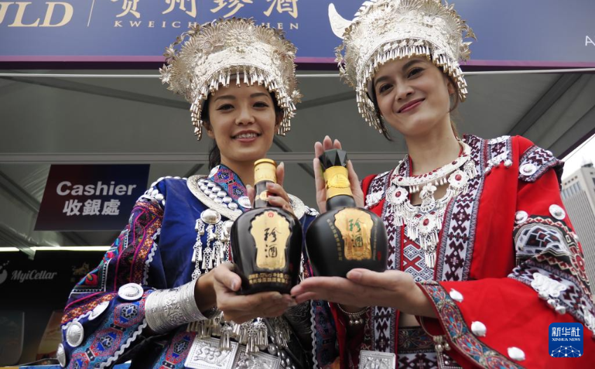 10月23日,在香港中环海滨,身穿民族服饰的工作人员在展示来自贵州的白酒。 10月23日,在香港中环海滨,身穿民族服饰的工作人员在展示来自贵州的白酒。