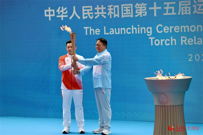 香港站首棒火炬手黄镇廷从香港特区署理行政长官陈国基手中接过圣火。人民网 严小晶摄 香港站首棒火炬手黄镇廷从香港特区署理行政长官陈国基手中接过圣火。人民网 严小晶摄