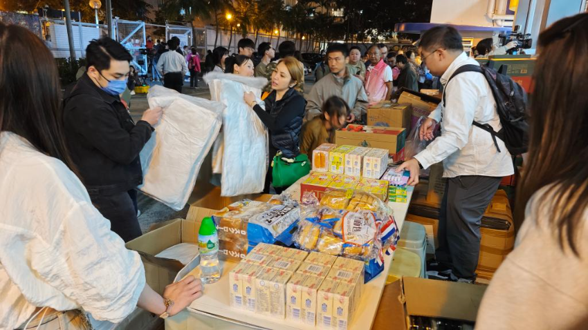 11月26日，受火灾影响的居民在跨部门援助站领取救援物资。