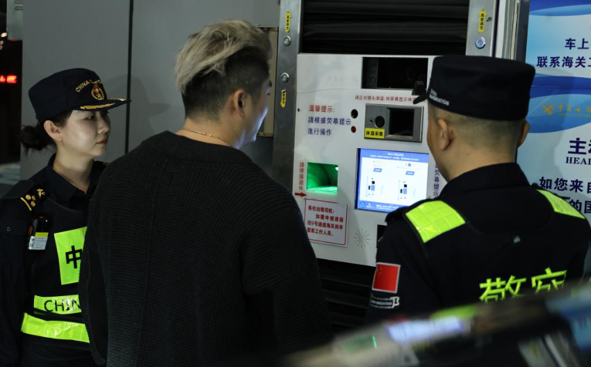 12月23日，“粤车南下”入境香港市区的首位通关车主彭先生（中）在“一站式”通道办理通关手续。