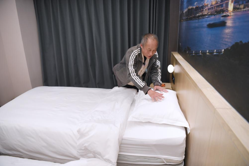 2025年11月28日，宏福苑居民邝佩麟在粤海酒店“爱心客房”里整理床铺。