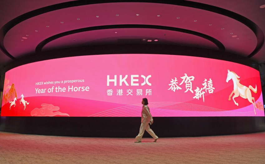 2月20日，一名女子从香港交易所电子显示屏前经过。当日，香港交易所农历马年首个交易日拉开帷幕。