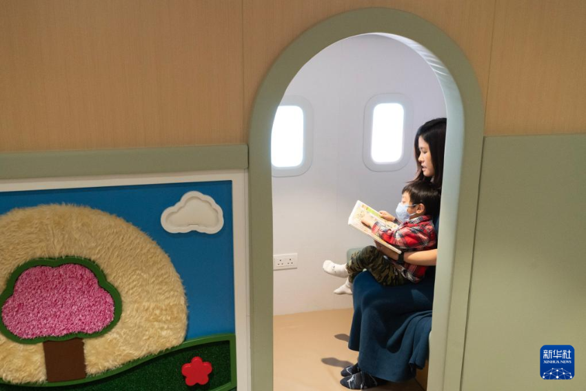 在位于香港国际机场一号客运大楼的“感知阁”内，邓女士陪伴被诊断为孤独症的儿子阅读搭乘飞机的绘本（3月31日摄）。
