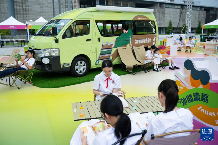4月23日，学生在流动图书车前阅读图书。