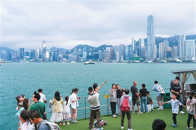 游客在香港维多利亚港游览。